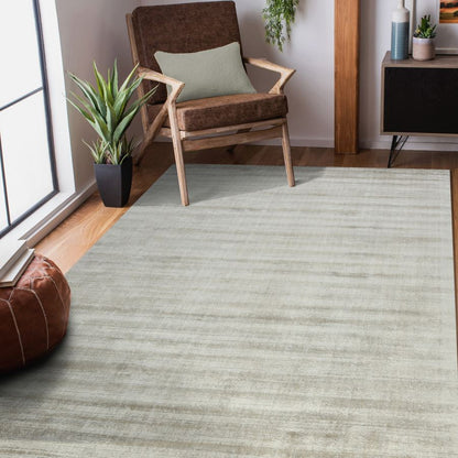 Living room with a green rug, wooden chair, and plants.