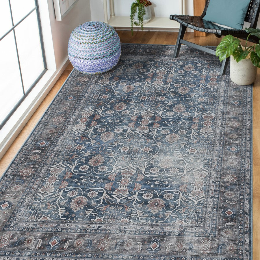 Decorative blue patterned rug in a room with a chair, ottoman, and plants.