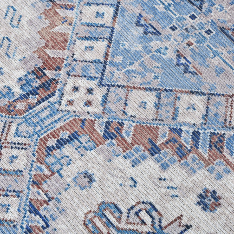 Close-up of a patterned rug with blue, brown, and beige colors.