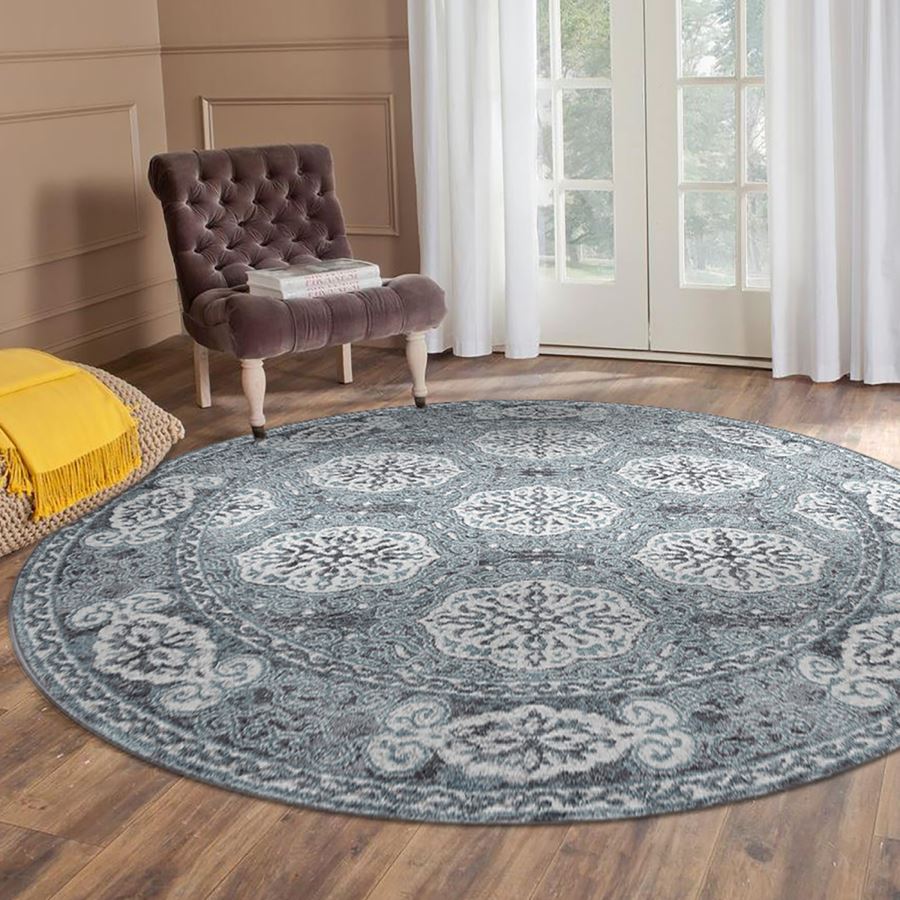 Round patterned rug on a wooden floor with a chair and yellow blanket in the background.
