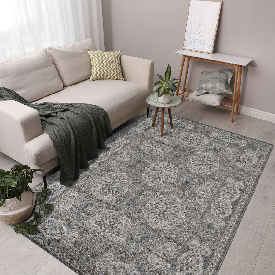 Living room with a patterned gray rug, beige sofa, and decorative items.