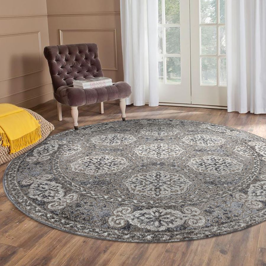 Round patterned rug on a wooden floor with a chair and yellow blanket in the background.