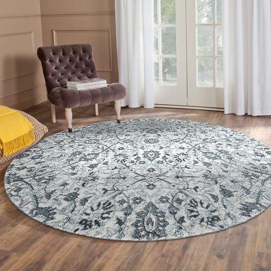 Round patterned rug on a wooden floor with a chair and yellow cushion in the background.