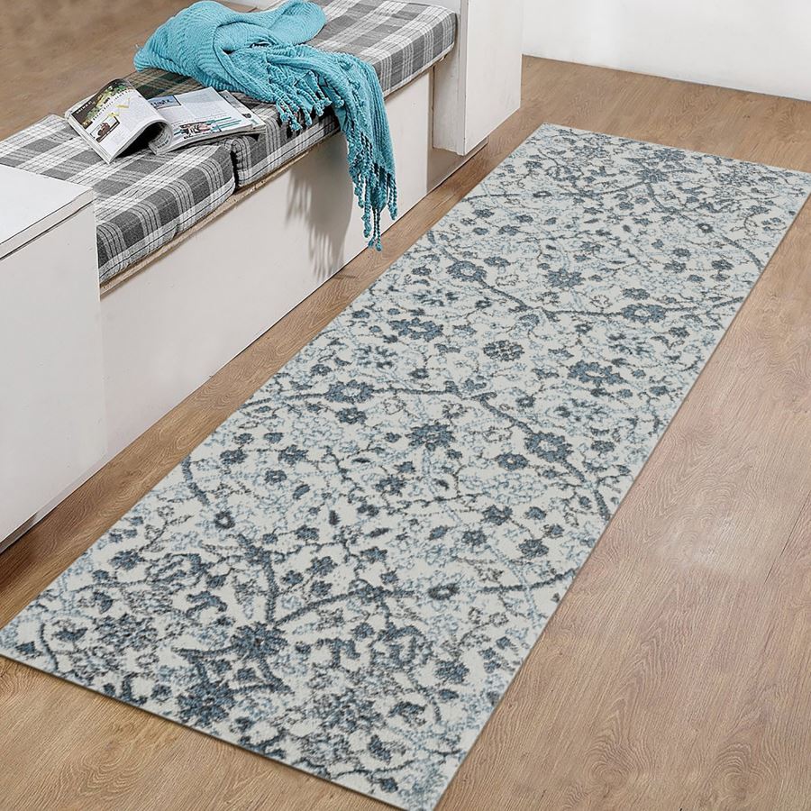 Floral patterned rug on a wooden floor with a bench and blue blanket.
