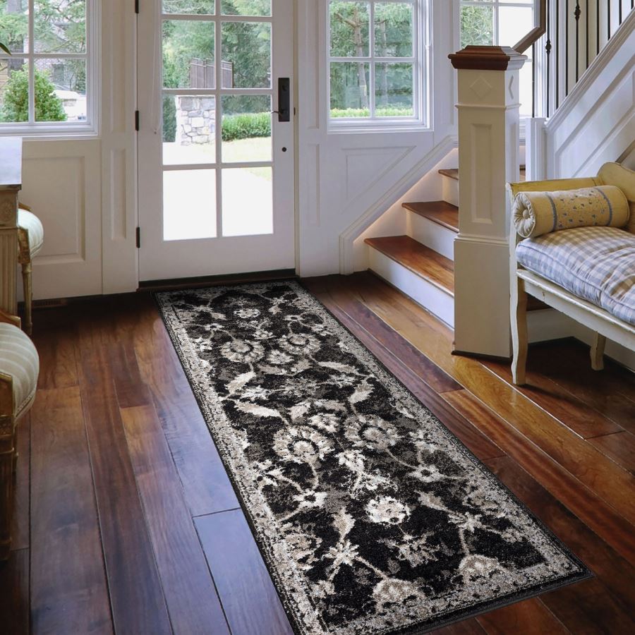 Long black and white floral patterned rug on a wooden floor in a home setting.