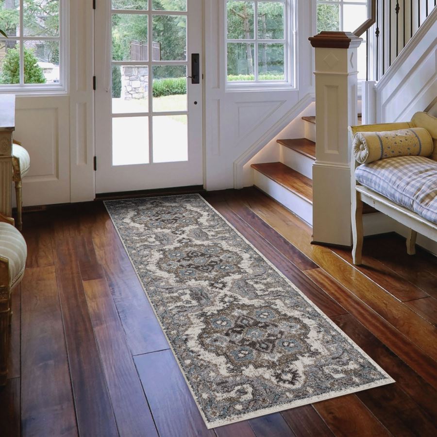 Decorative runner rug on a wooden floor in a home setting with a staircase and doors.