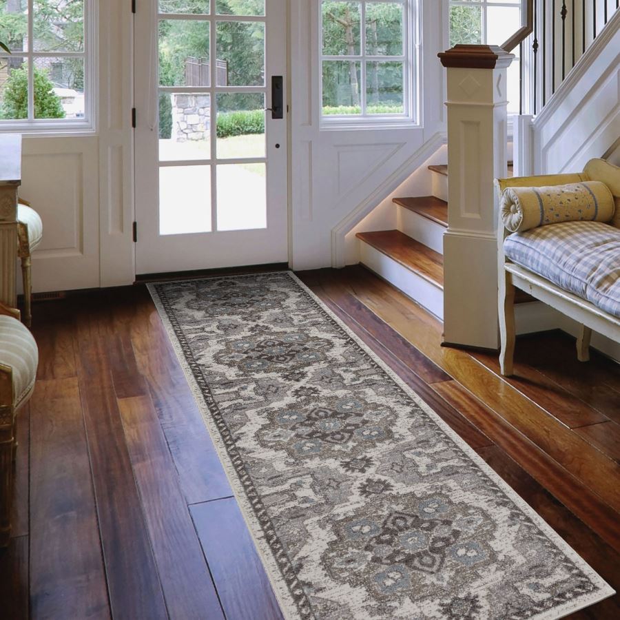 Decorative runner rug on a wooden floor in a home setting with a staircase and seating area.