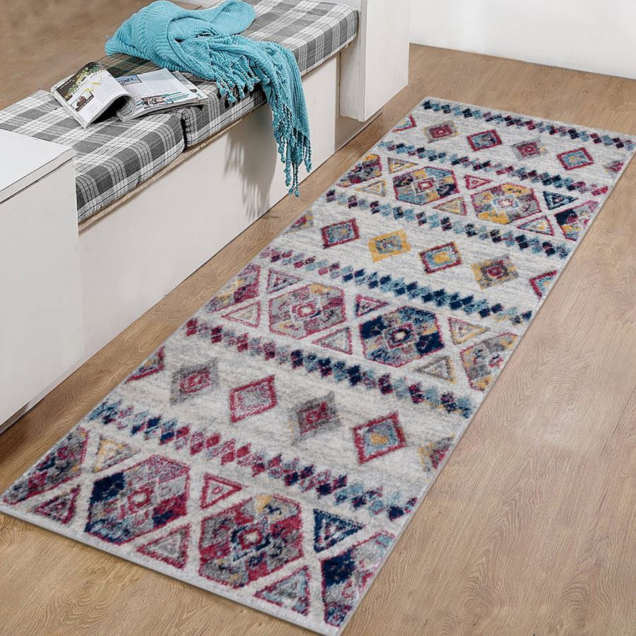 Patterned rug on a wooden floor with a bench and blue blanket in the background