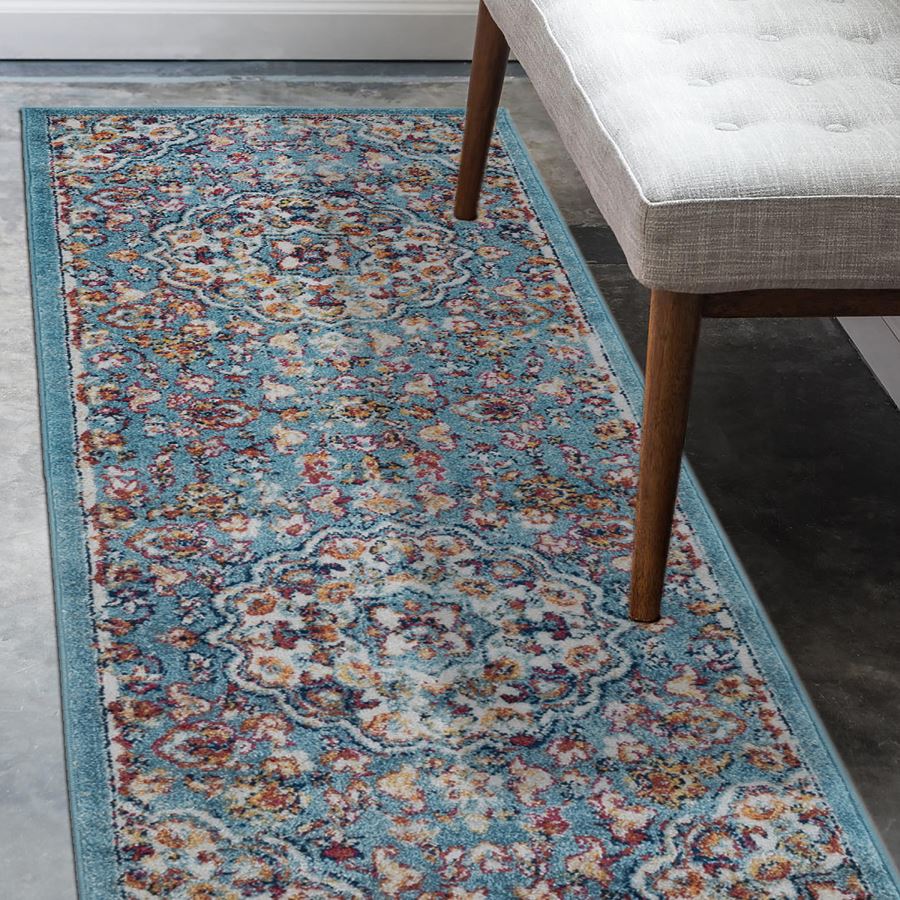 Decorative rug with floral pattern on a floor next to a chair.