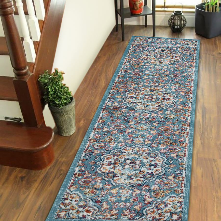 Decorative blue floral rug on a wooden floor next to a staircase