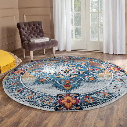 Round multicolored floral rug on a wooden floor with a chair and yellow pillow in the background.