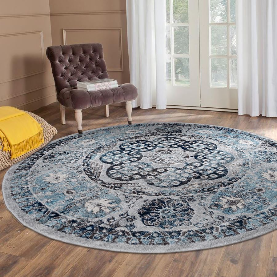 Round blue and gray patterned rug in a room with a chair and yellow blanket.