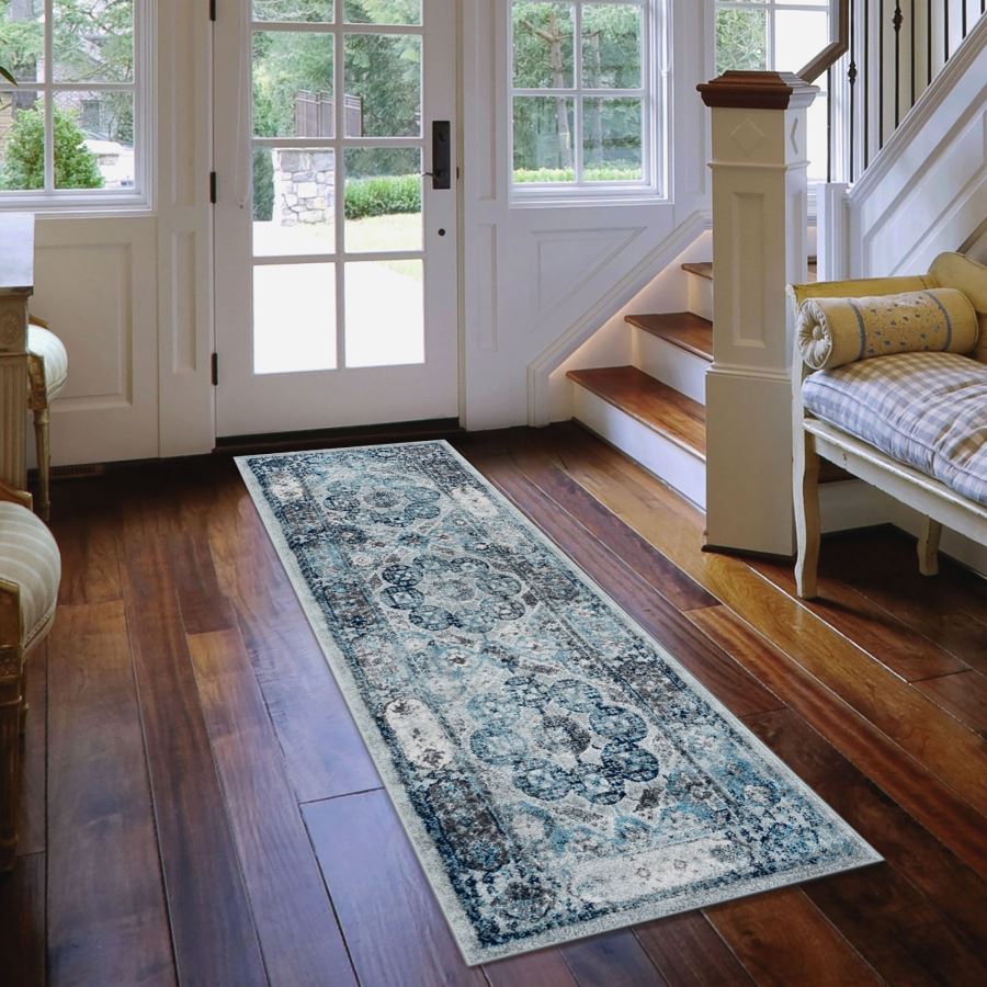 Long decorative rug on a wooden floor in a home setting with a staircase and doors.