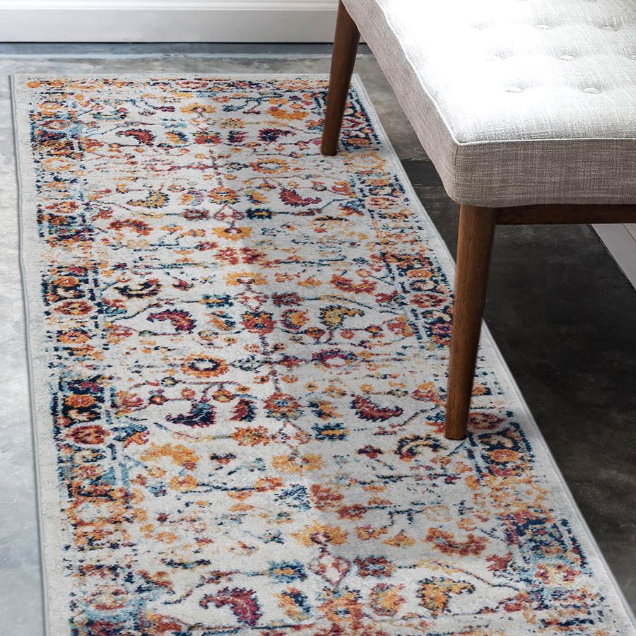 Multicolored floral patterned rug on a gray floor with a wooden bench.