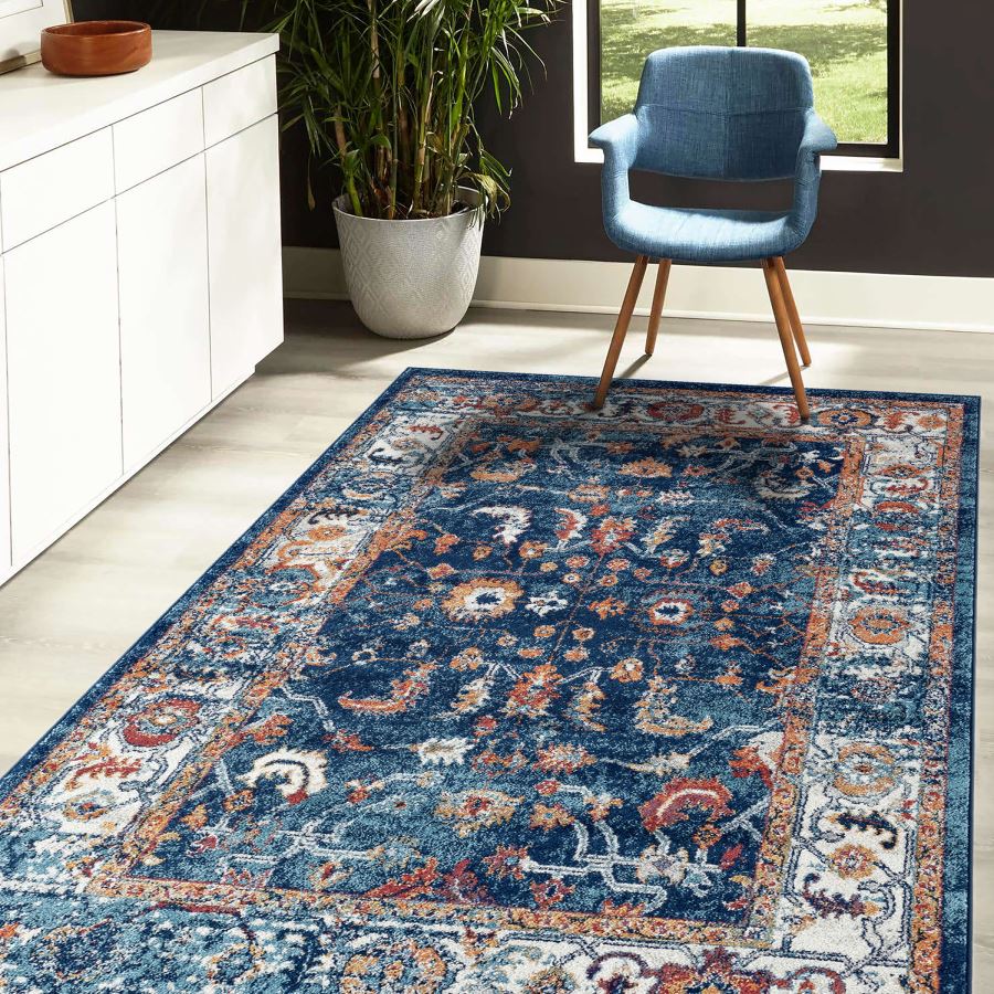 Decorative blue rug with intricate patterns in a room with a chair and plant.