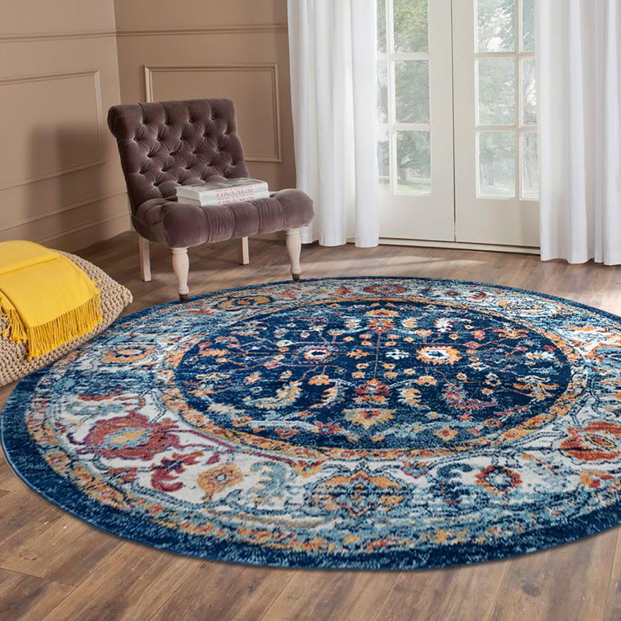 Round patterned rug on a wooden floor with a chair and yellow blanket in the background.