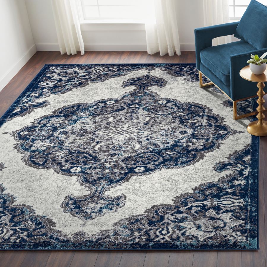 Decorative blue and white area rug in a living room setting with a blue sofa and gold side table.