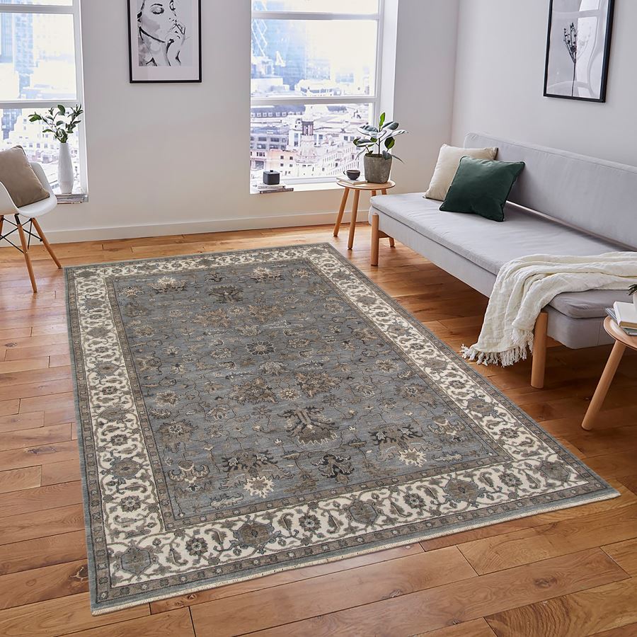 Living room with a patterned rug on wooden floor, sofa, and decor items.