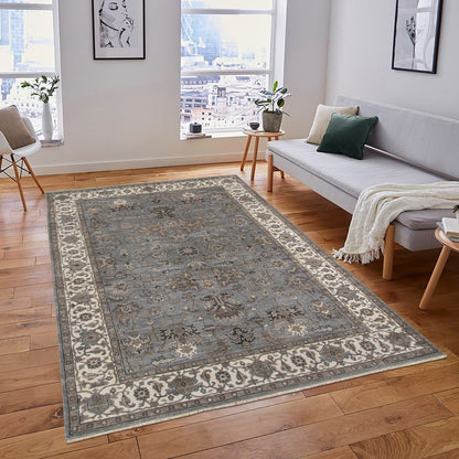 Living room with a patterned rug on wooden floor, sofa, and decor items.