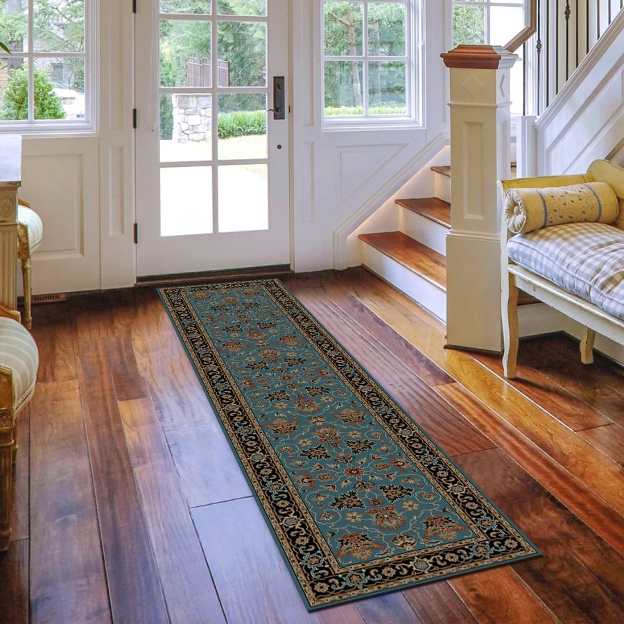 Decorative rug on a wooden floor in a home setting with a staircase and doors.