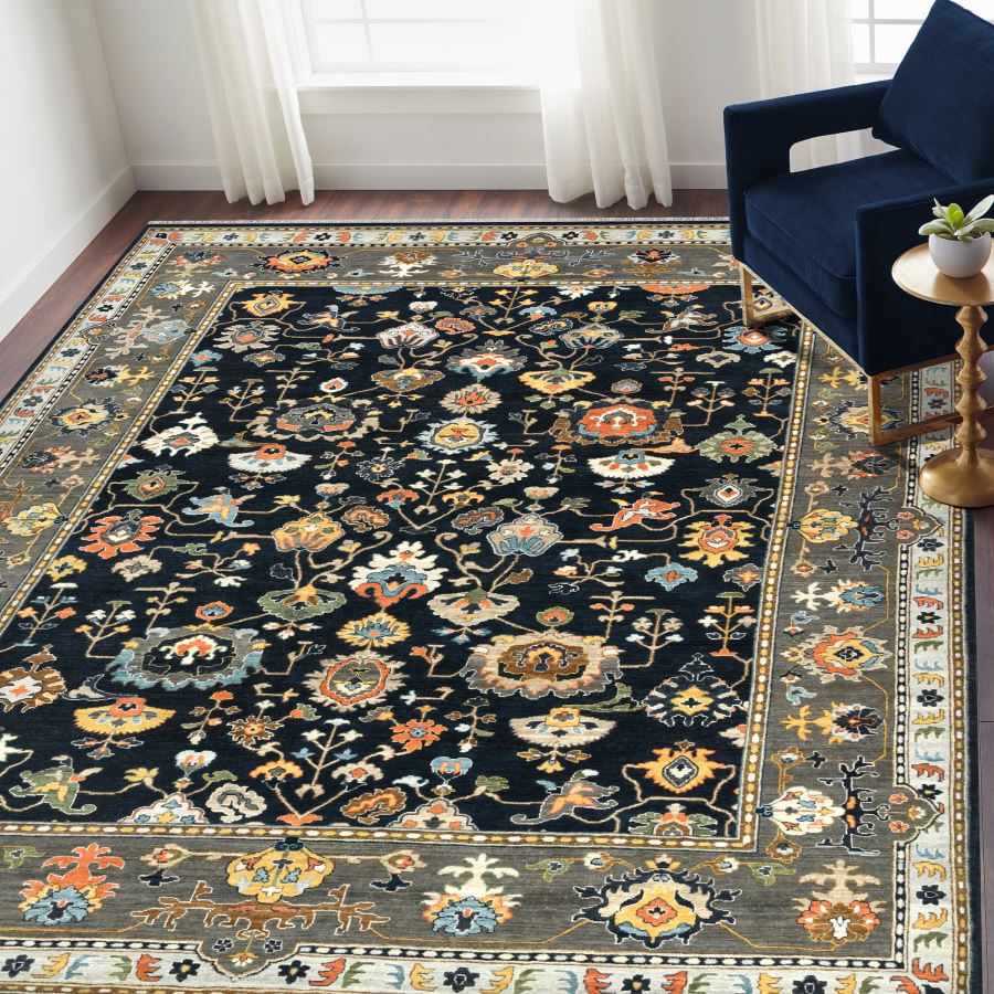 Decorative rug with floral pattern in a room with a blue chair and white curtains.
