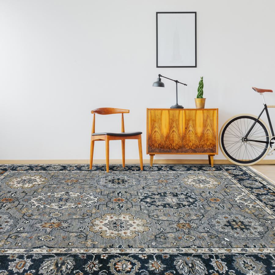 Living room with patterned rug, wooden chair, sideboard, and bicycle against a white wall.