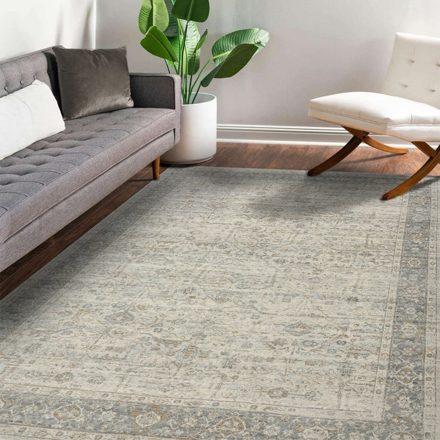 Living room with a gray rug, gray sofa, white ottoman, and potted plant.