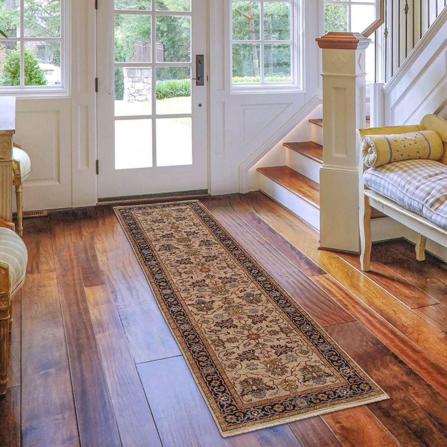 Long decorative rug on a wooden floor in a home interior with a staircase and doors.