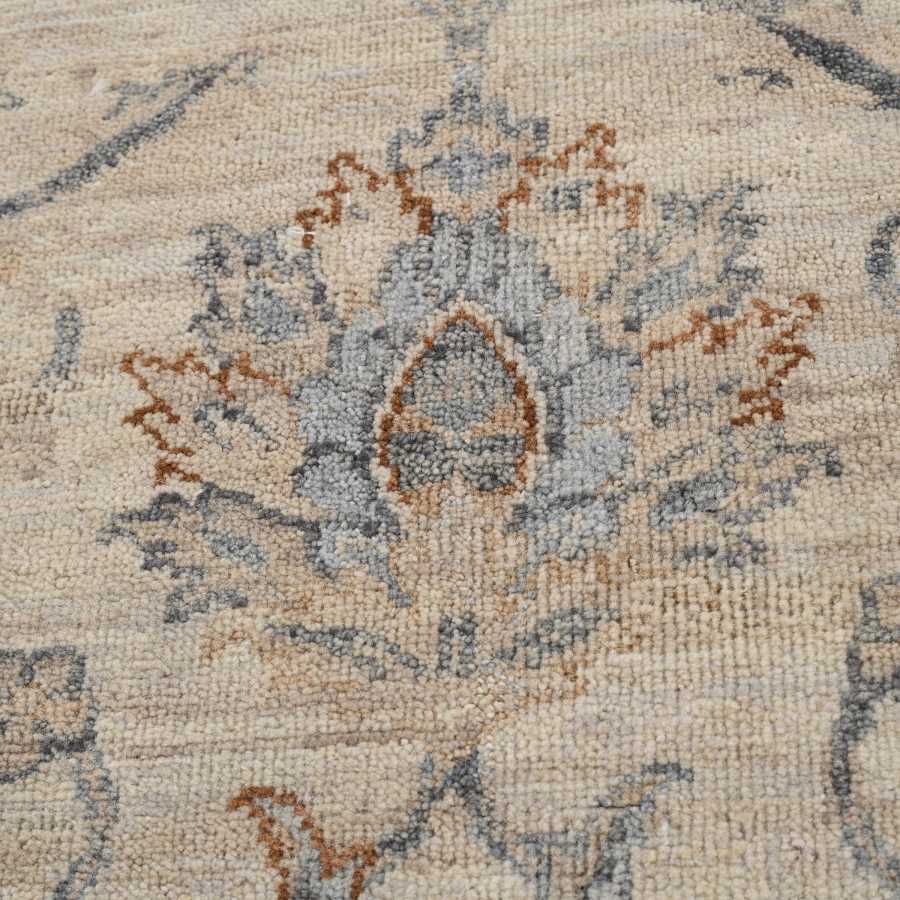 Close-up of a patterned rug with intricate designs in beige, brown, and blue.
