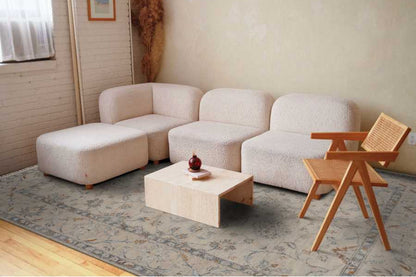 Beige sectional sofa with a wooden coffee table and chair in a living room setting.
