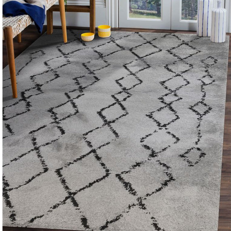 Gray area rug with black geometric pattern in a room with a bench and decor items.