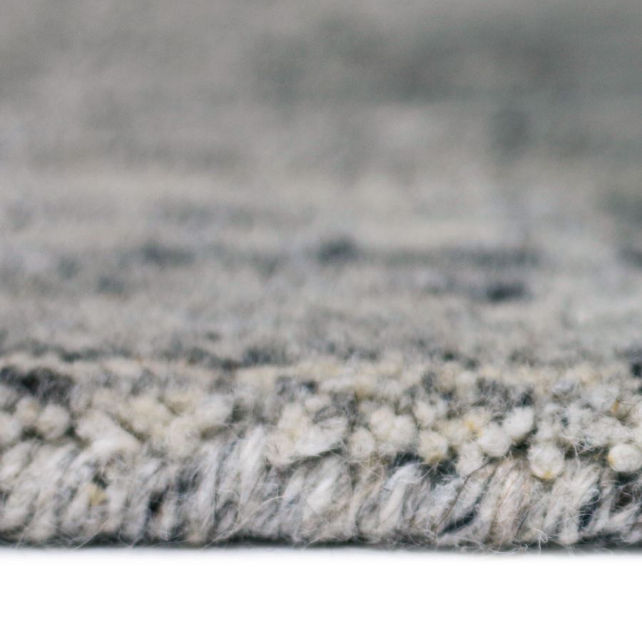 Close-up of a textured gray and white rug with a blurred background