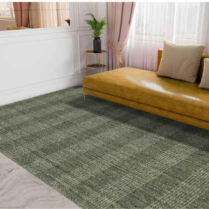 Brown sofa with beige cushions on a green checkered rug in a room with white walls and pink curtains.