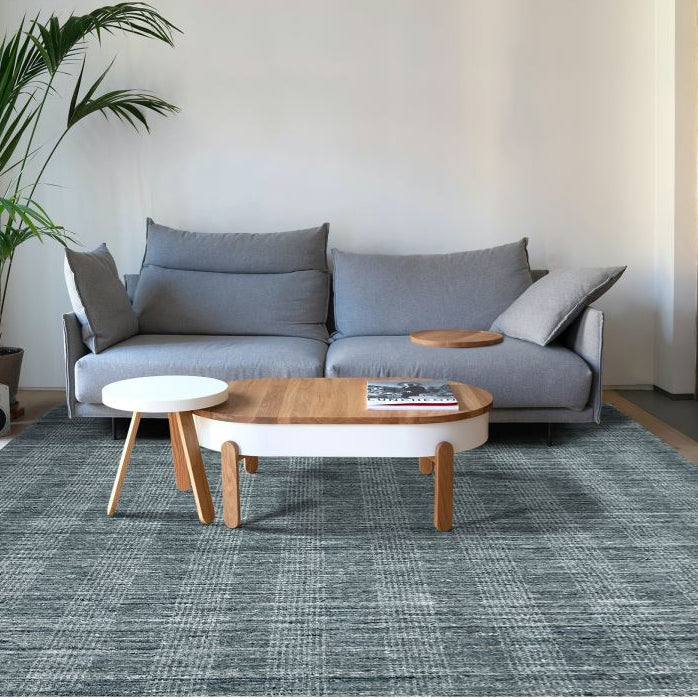 Modern living room with a gray sofa, wooden coffee table, and decorative plants.