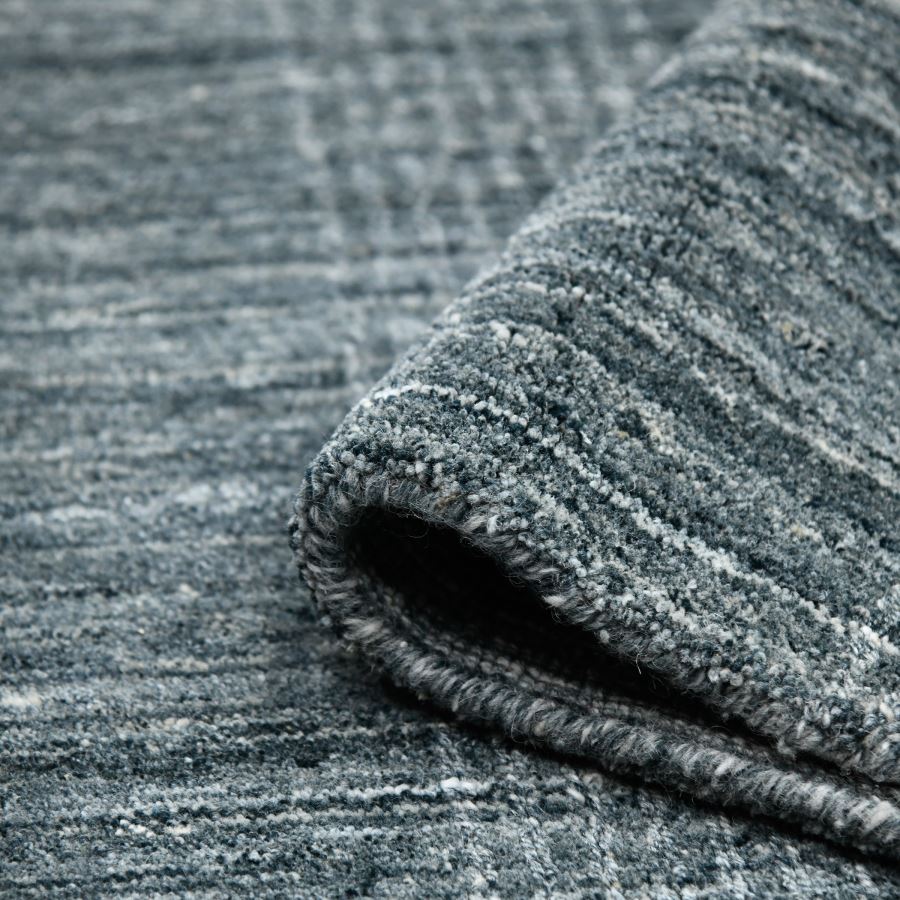 Close-up of a textured gray rug with a rolled edge.