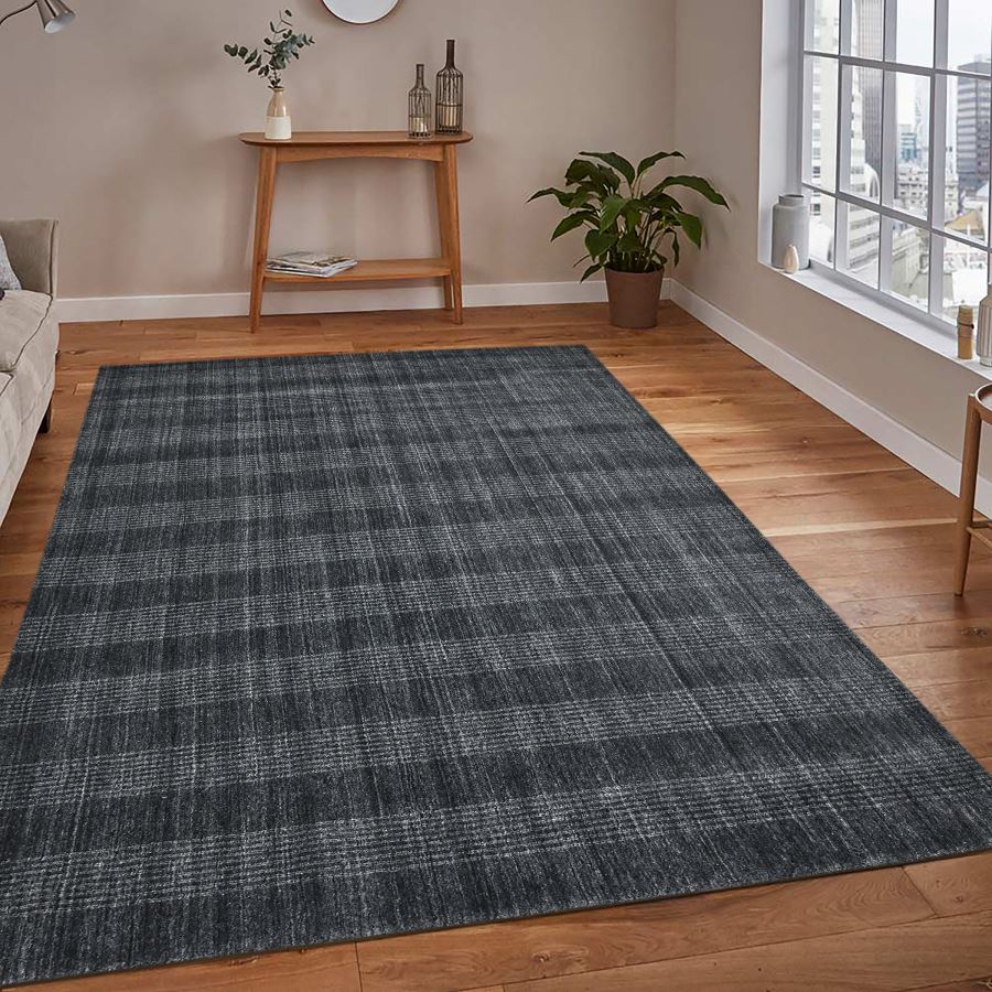 Gray checkered rug on a wooden floor with a side table and plant in the background.