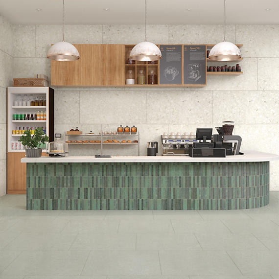 Modern kitchen counter with green tiled base and white countertop, featuring various kitchen appliances and shelves.
