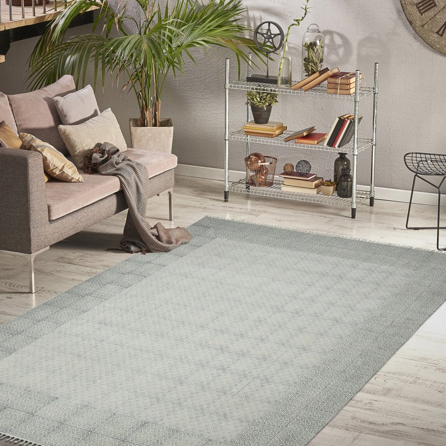 Living room with a gray rug, sofa, and decorative items on a shelf.