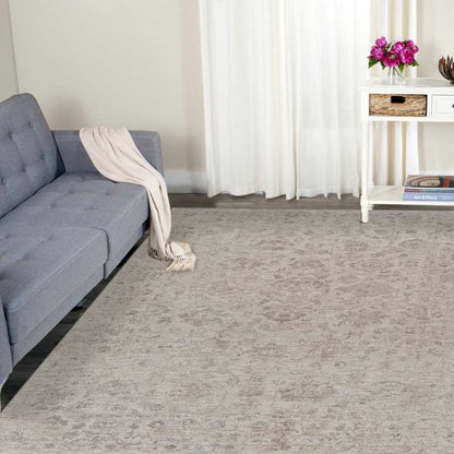 Living room with gray sofa, patterned rug, and white curtains