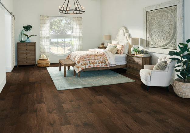 Neatly decorated bedroom with wooden flooring, bed, and furniture.