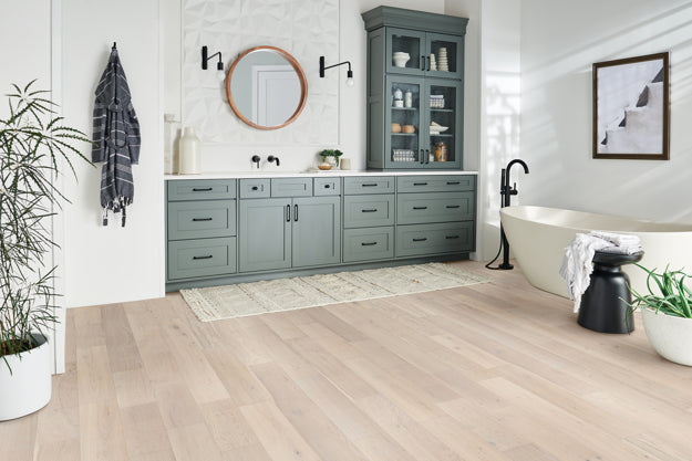 Modern bathroom with gray cabinets, freestanding bathtub, and decorative elements.