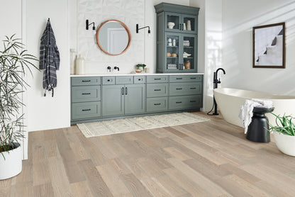 Modern bathroom with gray cabinets, freestanding bathtub, and wooden flooring.