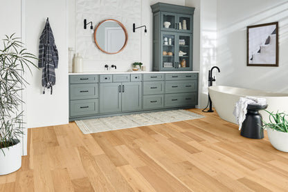 Modern bathroom with wooden floor, gray cabinets, and freestanding bathtub.