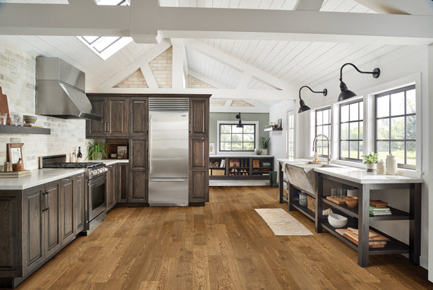 Modern kitchen with stainless steel appliances, wooden floors, and large windows.
