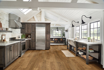 Modern kitchen with stainless steel appliances, wooden floors, and large windows.
