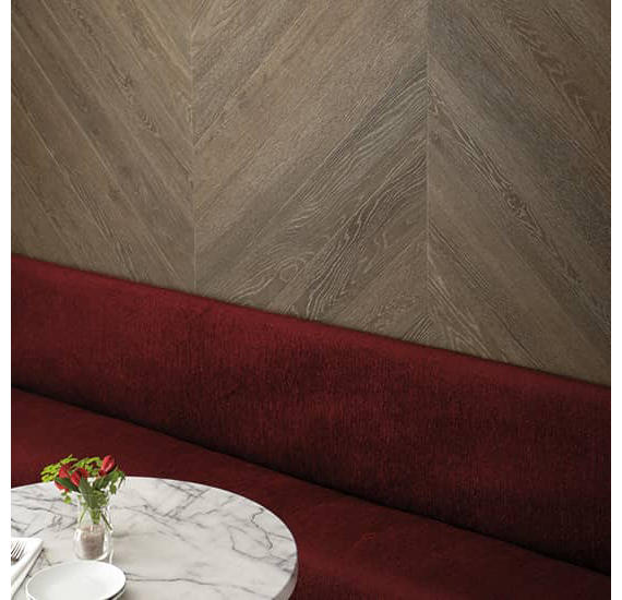 Maroon upholstered bench against a textured beige wall with a marble table and flowers.
