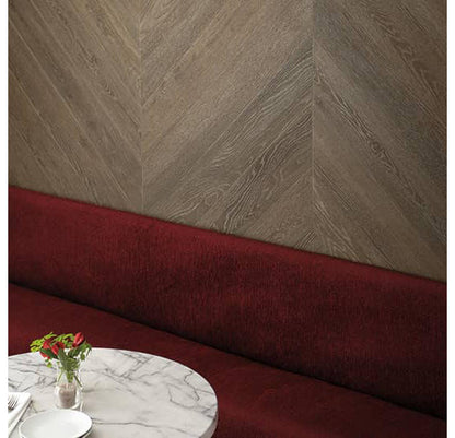 Maroon upholstered bench against a textured beige wall with a marble table and flowers.