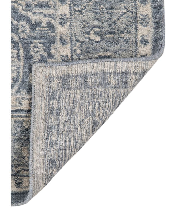 Close-up of a blue and gray patterned rug corner on a white background