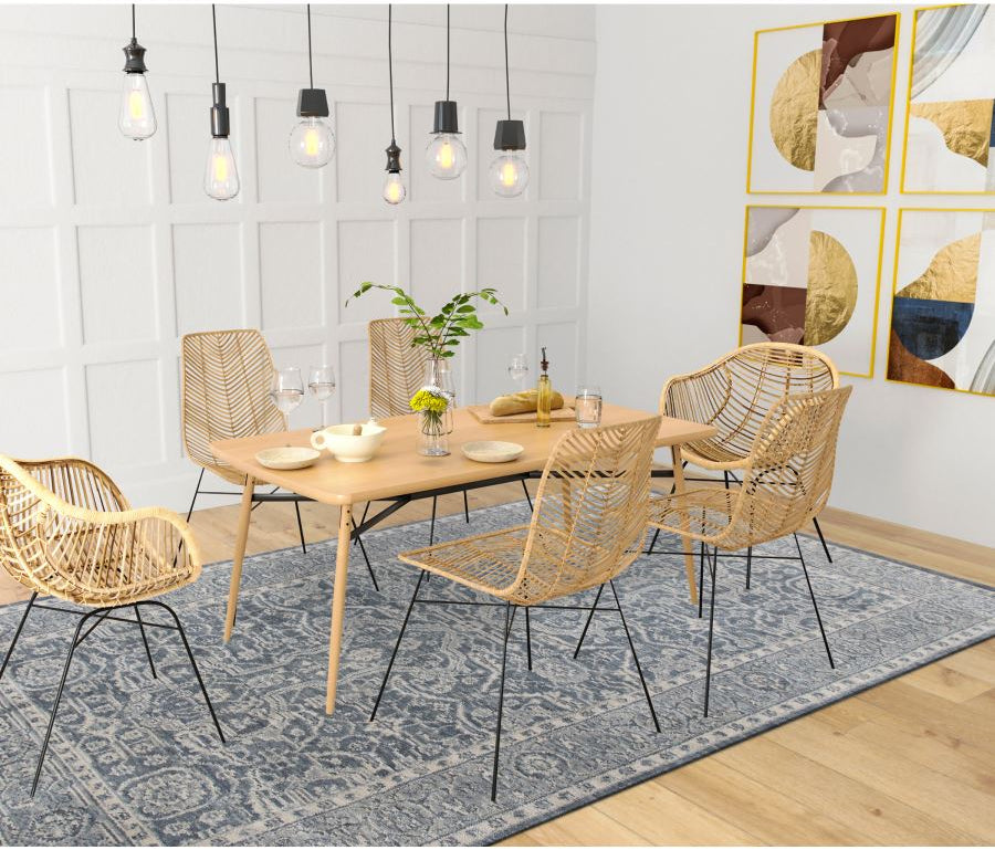 Dining room with wooden table and wicker chairs on a blue rug.