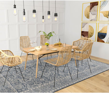 Dining room with wooden table and wicker chairs on a blue rug.